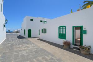 a white building with green doors and a courtyard at Casa la Mayor in Costa Teguise