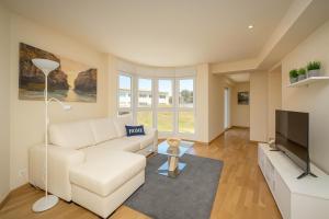 a living room with a white couch and a flat screen tv at Las Catedrales in Foz