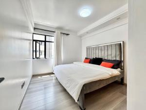 内罗毕Homey Hideout的一间卧室配有一张带橙色枕头的大床
