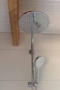 a shower in a bathroom with a shower head at Tiny house Friesland nabij het water met hottub Fjild Hûske in Echtenerbrug