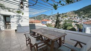 a wooden table and chairs on a balcony with a view at Lithos Hydra in Hydra