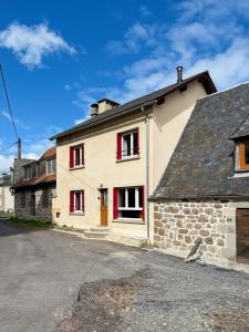ein weißes Haus mit roten Fensterläden in einer Straße in der Unterkunft Vallée de la Jordanne, Maison cosy 6pers, terrasse in Saint-Julien-de-Jordanne
