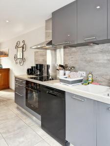 eine Küche mit schwarzen Geräten und einer weißen Arbeitsplatte in der Unterkunft Vallée de la Jordanne, Maison cosy 6pers, terrasse in Saint-Julien-de-Jordanne