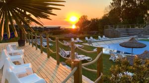 a group of chairs and a pool with the sunset at Hotell Kneippbyn Resort Visby in Visby