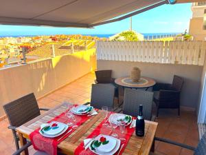 a table with plates and wine glasses on a balcony at Comfortable 2 bed in Arguineguín in Arguineguín
