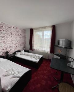 ein Hotelzimmer mit zwei Betten und einem Fernseher in der Unterkunft Pensiunea Lotus Baile 1 Mai in Baile Unu Mai