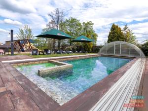una piscina con sombrilla y un parque infantil en Hotel Benica, en Benešov