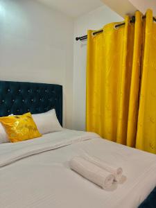 a bedroom with two beds with yellow curtains at Koki Bnbs Kamakis in Ruiru