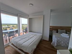 a bedroom with a bed and a balcony with a table at Apartamento con piscina in Matalascañas +21 photos