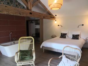 朱里耶纳La maison de Bruno的一间卧室配有一张床、两把椅子和一个浴缸