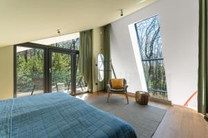 a bedroom with a bed and a chair and windows at MÁK Kismaros in Kismaros