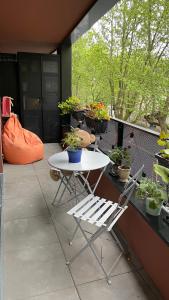 a white table and chairs on a balcony with potted plants at Cosy and Spacious appartement near metro line 4 & RER B in Bagneux