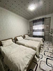 a room with three beds and a rug at Family hostel Toshkent in Toshkent-Passajir Bekati