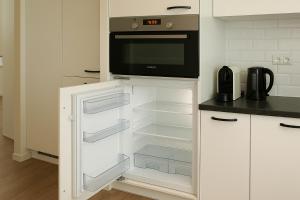 a kitchen with an open refrigerator with a microwave at Reza Almere in Almere