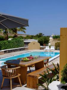 a table and chairs next to a swimming pool at Beautiful Santorini Villa 3 Bedrooms Villa Phos Private Pool & Lovely Sea View Exo Gialos in Karterados