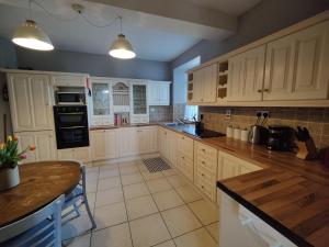 a large kitchen with white cabinets and black appliances at Rustic Pub Stay - 20 minutes from Killarney! in Rathmore