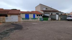 een rij huizen met blauwe deuren op een parkeerplaats bij Oacys in Le Barcarès