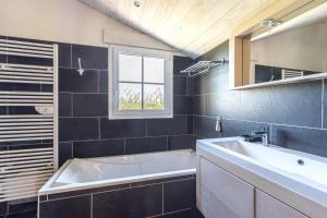 a bathroom with a white tub and a sink at L’Échappée du Port - Grand Jardin in Bouin