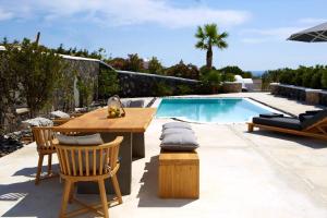 a patio with a table and chairs next to a swimming pool at Lovely Santorini Villa 3 Bedrooms Villa Petra Private Pool & Outdoor Dining Area Exo Gialos in Karterados +5 photos