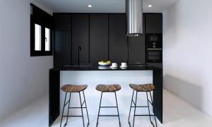 eine Küche mit einer schwarzen Insel mit zwei Barhockern in der Unterkunft Magnificent Mykonos Villa Villa Rikei 5 Bedrooms Unique Aegean Sea Views in Psarrou