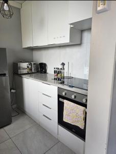 a kitchen with white cabinets and a stove top oven at Neat, instaworthy, self-checkin flat in Pretoria in Pretoria