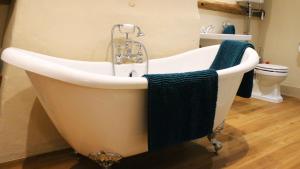 eine Badewanne mit einer Dusche und einem blauen Handtuch in der Unterkunft Chinnerys Country Cottage in Cavendish + 25 Fotos