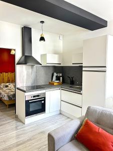 a kitchen with white cabinets and a couch at Studio Bohème in Gare du Nord
