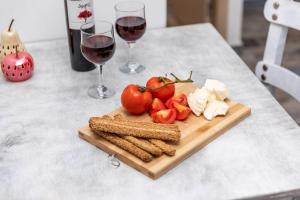 a cutting board with tomatoes and cheese and two glasses of wine at Luxury Naxos Suites Superior Apartment With Balcony Steps Away From The Main Square Saint George in Naxos Chora