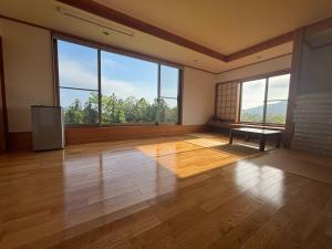 an empty room with large windows and a wooden floor at サウナパラダイス富山 in Minamiboso