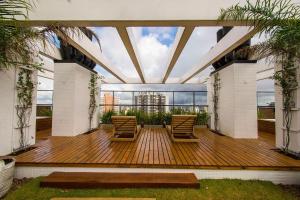 a deck with two chairs and a large window at VILLA DI TONDO HOUSE - APARTAMENTO ESPETACULAR in Bento Gonçalves