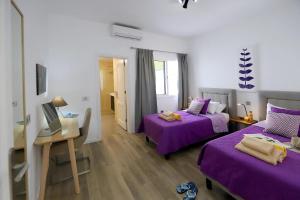 pokój z dwoma łóżkami z fioletowymi prześcieradłami i biurkiem w obiekcie Luxury Puerto Calero Villa Casa Nublo 3 Bedrooms Private Pool Terrace With Seaviews Lanzarote w mieście Puerto Calero +32 zdjęcia