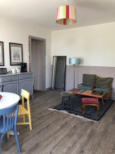 a living room with a couch and a table and chairs at l'appart de la Maison du Hommeel in Gratot