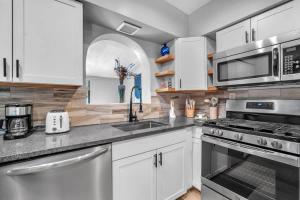 a kitchen with white cabinets and stainless steel appliances at Newly Renovated - Sunny Family Haven in Pompano in Pompano Beach