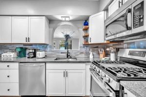 a kitchen with white cabinets and a stove top oven at Newly Renovated - Sunny Family Haven in Pompano in Pompano Beach