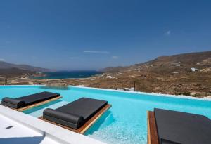 ein Swimmingpool mit zwei Liegestühlen im Wasser in der Unterkunft Extraordinary Mykonos Villa Villa Shifu 6 Bedrooms Unique Aegean Sea View in Ano Mera