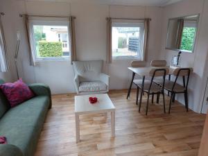 a living room with a couch and a table and chairs at Camping Alkenhaer Appelscha Chalet 034 in Appelscha