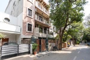 a building with a tree on the side of a street at Homlee-Green Luxury 3BHK-South DEL-NFC-Fortis Hospital in New Delhi
