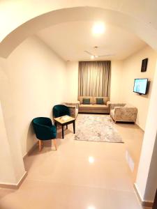 Una sala de estar con un sofá, una mesa y sillas. en الوادي - نسائم صلالة للشقق الفاخرة Nassayem Salalah Al-Wadi, en Salalah