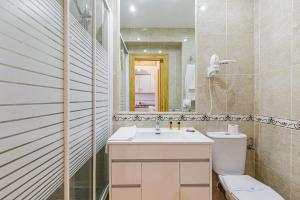 ein Badezimmer mit Toilette, Waschbecken und Spiegel in der Unterkunft Apartamentos Tamarindos in Benalmádena