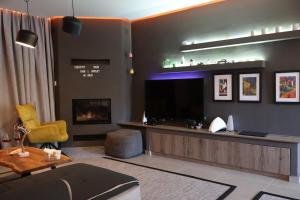 a living room with a tv and a yellow chair at One Luxury House Above The Sea in Plakias