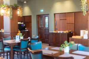 a dining room with tables and chairs and a kitchen at Hotel Cēsis in Cēsis