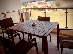 a wooden table and chairs on a balcony with a view at Airport Sea View - Studio - 15 mins from Athens Airport in Artemida