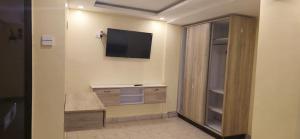 Ein Zimmer mit einem an der Wand befestigten Fernseher und einem Schreibtisch in der Unterkunft Desert Sky Hotel in Isiolo