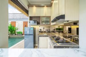 a kitchen with a refrigerator and a swimming pool at Modern 3BDR Villa - Between Canggu & Seminyak in Kerobokan