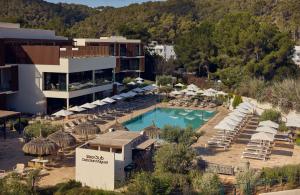 an aerial view of a hotel with a pool and chairs at Cala San Miguel Ibiza Resort, Adults only, Curio Collection by Hilton in Puerto de San Miguel