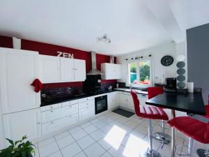 een keuken met rode en witte kasten en een tafel bij Casa Bords de Loire in Mûrs-Érigné +19 foto's