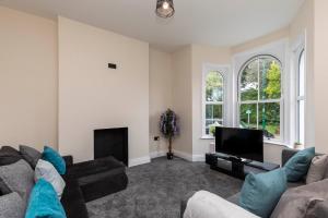 a living room with a couch and a television at Victoria Cottage Seaside - Spacious 4-BR in Bognor Regis,close to Beachfront & 2 minutes from Butlins Holiday Camp in Felpham