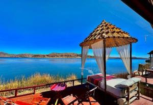 a bed and an umbrella next to a body of water at Titicaca posada del sol lodge in Puno