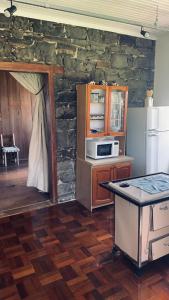 a kitchen with a stone wall and a counter with a microwave at Almorão in São Francisco de Paula