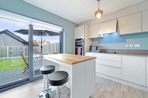 a kitchen with white cabinets and a large window at Westpoint in Donegal